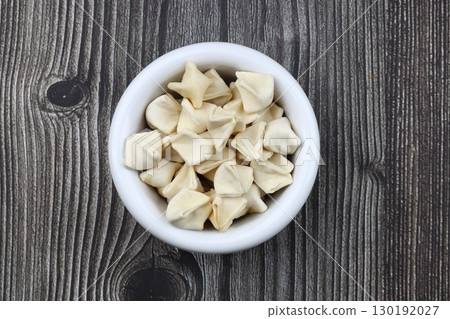handmade manti (turkish ravioli type dumplings) on wooden bowl, before cooking handmade manti (turkish ravioli type dumplings) on wooden bowl, before cooking 130192027