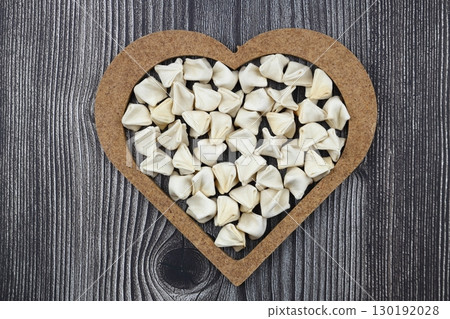 handmade manti (turkish ravioli type dumplings) on wooden heart shape bowl, before cooking handmade manti (turkish ravioli type dumplings) on wooden heart shape bowl, before cooking 130192028