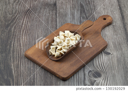 handmade manti (turkish ravioli type dumplings) on wooden scoop, before cooking handmade manti (turkish ravioli type dumplings) on wooden scoop, before cooking 130192029