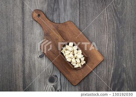 handmade manti (turkish ravioli type dumplings) on wooden scoop, before cooking handmade manti (turkish ravioli type dumplings) on wooden scoop, before cooking 130192030
