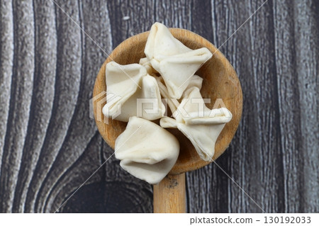 handmade manti (turkish ravioli type dumplings) on wooden spoon, before cooking. Macro handmade manti (turkish ravioli type dumplings) on wooden spoon, before cooking. Macro 130192033