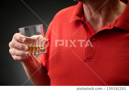 Closeup  a torso dressed in a red sweatshirt tasting a good bourbon 130192201