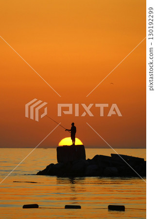 Tourists on holiday in the famous resort town of Bodrum spend time fishing at sunset. 130192299
