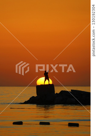 Tourists on holiday in the famous resort town of Bodrum spend time fishing at sunset. 130192304