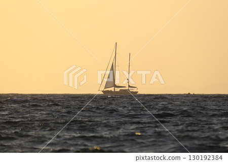 Alone sailboat at sunset. Atmospheric seascape with orange sun. 130192384
