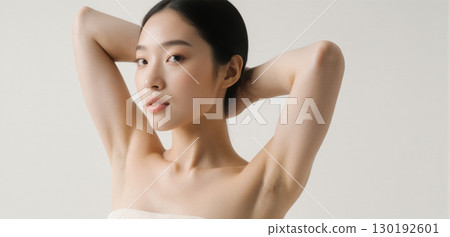 Young woman posing with arms raised showing smooth clean armpits on light background 130192601