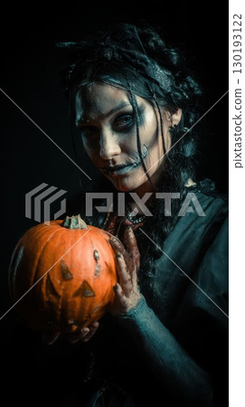 Dark figure with a carved pumpkin 130193122