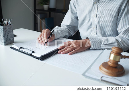 Legal justice man working on desk reading supportive documents to determine the consulting case Legal justice man working on desk reading supportive documents to determine the consulting case 130193312