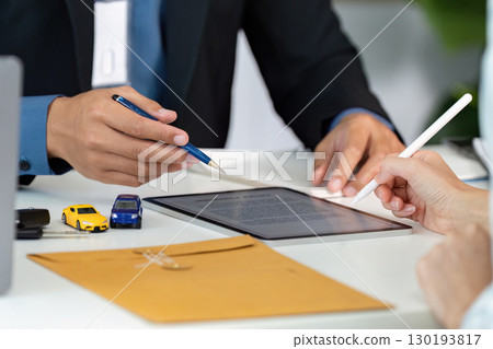 Insurance Consultation. Discussing car insurance policy with client using tablet and model cars. Insurance Consultation. Discussing car insurance policy with client using tablet and model cars. 130193817