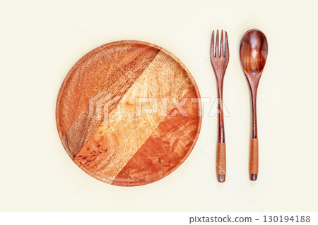 Eco friendly minimalistic composition with wooden plate, wooden spoon and fork on a light background. Table set, plate, fork, knife made of natural wood. Empty dish for presentation your products 130194188