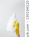 Female hand in a yellow rubber glove holding a white branding mockup of laundry gel packaging. Household cleaning and hygiene concept packaging 130194520