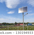 Streetlight equipped with a solar panel on top. Renewable energy sources, LED light poles. Solar-powered streetlight installed along a country road in a village. Clear sky, sunny day. 130194933