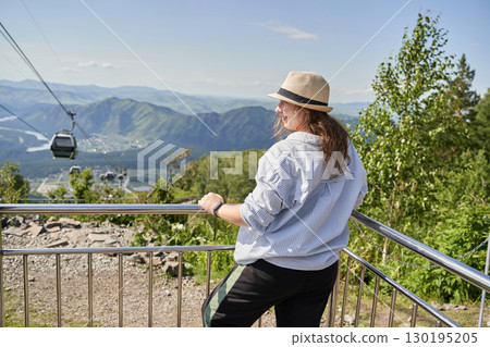 Caucasian young female admiring mountain view at scenic cable car destination 130195205