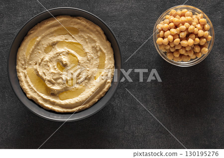 hummus with butter and chickpeas in bowls on dark table, top view 130195276
