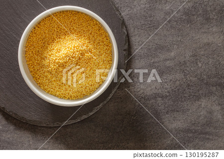 millet groats in bowl on dark countertop, top view millet groats in bowl on dark countertop, top view 130195287