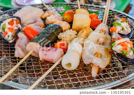 various seafood on skewers and seashells are grilled various seafood on skewers and seashells are grilled 130195301