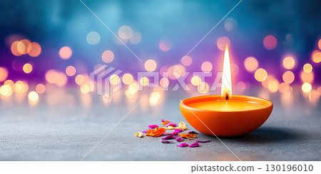 Traditional oil lamp with glowing flame placed on a surface, surrounded by soft bokeh lights 130196010