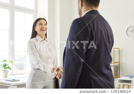 Business people shaking hands standing in office making a good deal. Partnership concept. Business people shaking hands standing in office making a good deal. Partnership concept. 130196624