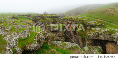 Rock formations and cracks covered with green moss in a misty landscape Rock formations and cracks covered with green moss in a misty landscape 130196862