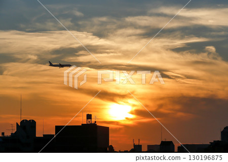 A sunset-colored sky and a landing plane 130196875