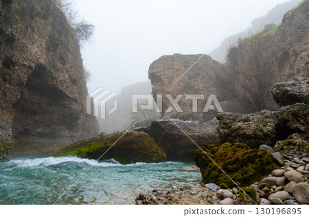 Rocky gorge with a turquoise river in misty weather Rocky gorge with a turquoise river in misty weather 130196895