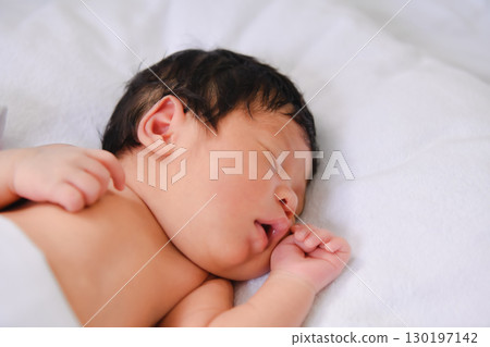 A peaceful newborn baby sleeping soundly on a soft blanket, embodying innocence and tranquility in a serene environment. 130197142