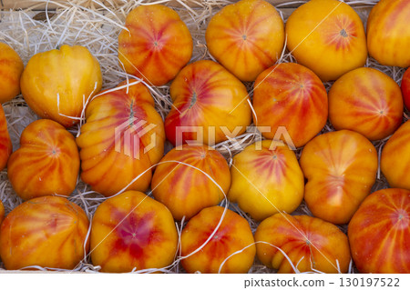 Fresh, ripe, colorful striped tomatoes displayed on straw in a wooden crate at a farmers market in Nyons, France 130197522