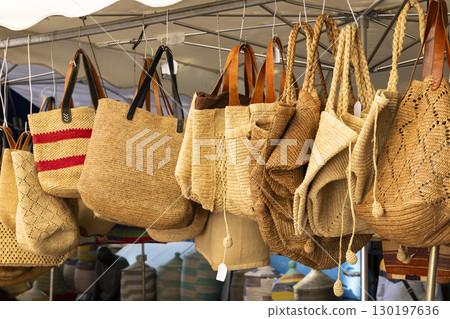 Raffia bags hanging at a market stall in Nyons, France 130197636