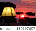 Fiery Red Sunset Over the Sea with an Illuminated Foreground Lamp 130197657