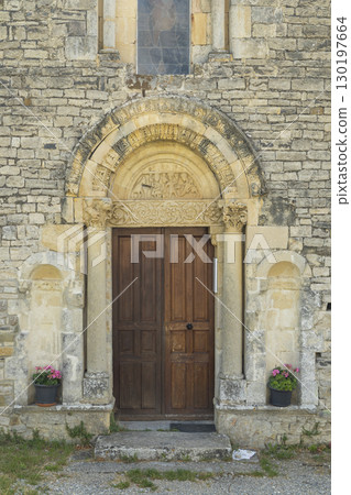 Romanesque Portal of Sainte Jalle Church in Drome, France, Showing Intricate Stone Carvings and Wooden Door 130197664
