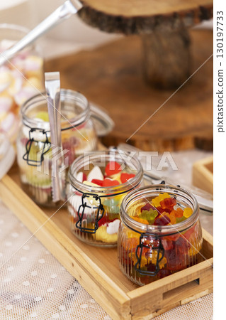 Colorful gummy candies in glass jars on wooden tray, celebrating a special occasion 130197733