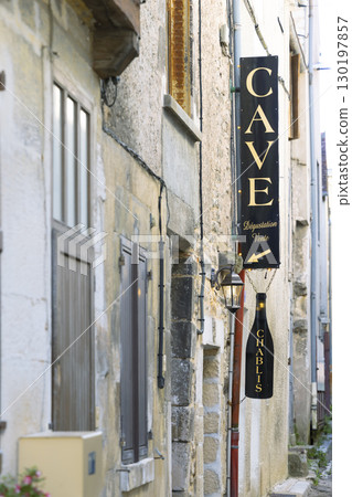 Chablis wine cellar sign hanging in narrow street in France 130197857