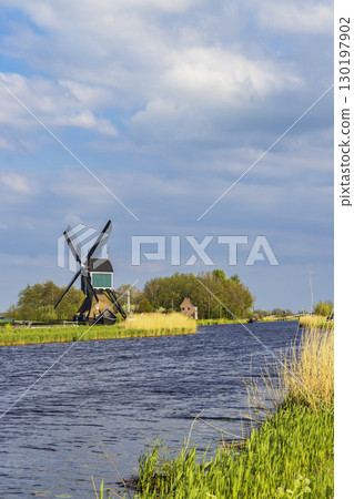 Traditional dutch windmill standing on the bank of a canal in Brandwijk, Netherlands 130197902