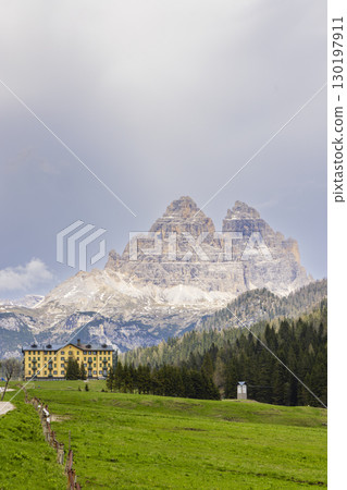 Tre Cime di Lavaredo towering over hotel and green meadow in Auronzo di Cadore, Italy 130197911