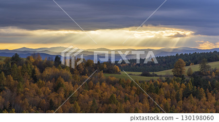 Sun rays shining through clouds over colorful autumn forest landscape with Low Tatras Sun rays shining through clouds over colorful autumn forest landscape with Low Tatras 130198060