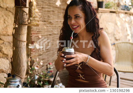 Woman Enjoying a Traditional Mate Beverage in a Rustic Outdoor Setting 130198296