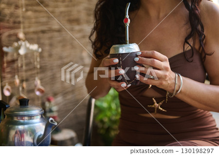 Woman Enjoying a Traditional Yerba Mate Drink in a Cozy Outdoor Setting 130198297