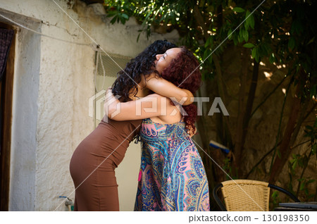 Two Women Sharing a Warm Hug in an Outdoor Garden Setting 130198350