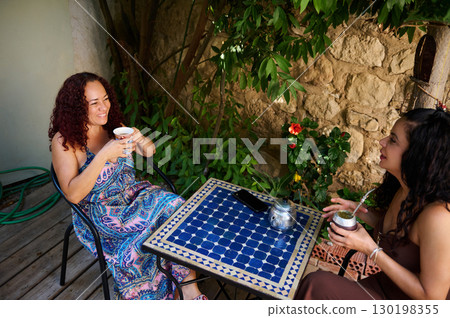 Two Women Enjoying Refreshing Drinks Outdoors in a Garden Setting Two Women Enjoying Refreshing Drinks Outdoors in a Garden Setting 130198355