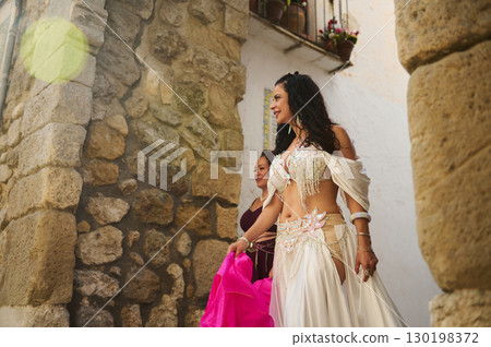 Elegant Dancer in Traditional Costume by Rustic Stone Walls 130198372