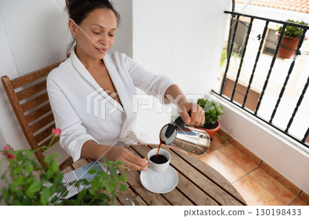 Woman Enjoying Coffee on a Cozy Balcony During a Refreshing Morning 130198433