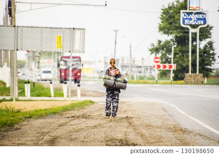 Hitchhiking. Girl auto-stopper. The girl with the backpack stops the car. Voting on the track. Hitchhiking. Girl auto-stopper. The girl with the backpack stops the car. Voting on the track. 130198650