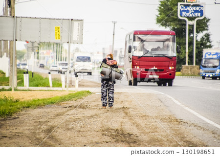 Hitchhiking. Girl auto-stopper. The girl with the backpack stops the car. Voting on the track. Hitchhiking. Girl auto-stopper. The girl with the backpack stops the car. Voting on the track. 130198651