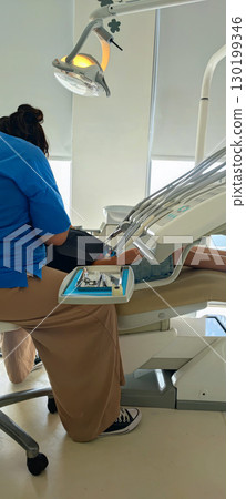 Dental care for children in a modern clinic: a dentist treats a young patient in a chair with a lamp and instruments. Concept: healthcare, prevention, hygiene Dental care for children in a modern clinic: a dentist treats a young patient in a chair with a lamp and instruments. Concept: healthcare, prevention, hygiene 130199346