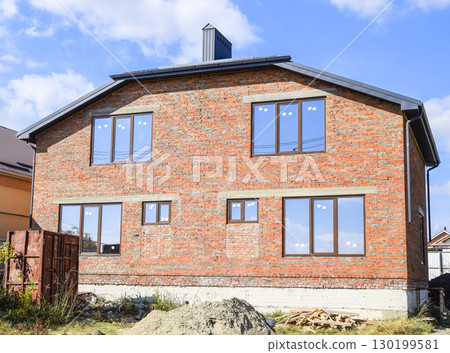 Two-storey house made of red brick. Metal-plastic windows. Newly built house. Two-storey house made of red brick. Metal-plastic windows. Newly built house. 130199581