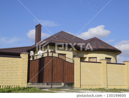 Decorative metal on the roof of a brick house. Fence made of corrugated metal. Decorative metal on the roof of a brick house. Fence made of corrugated metal. 130199600