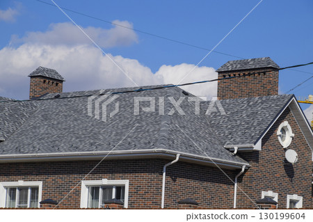 Asphalt shingle. Decorative bitumen shingles on the roof of a brick house. 130199604
