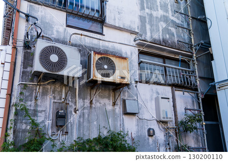 An old building in Atami with an air conditioner outdoor unit attached to the wall An old building in Atami with an air conditioner outdoor unit attached to the wall 130200110