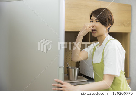 一名繫著圍裙的女子打開冰箱 一名繫著圍裙的女子打開冰箱 130200779