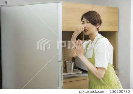 一名繫著圍裙的女子打開冰箱 一名繫著圍裙的女子打開冰箱 130200780